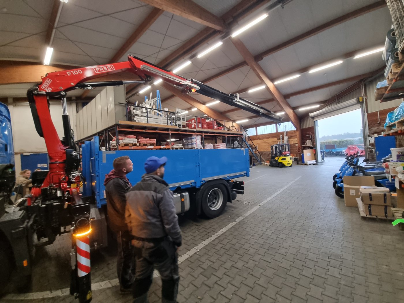 Kollegen in der Lagerhalle am LKW mit Ladekran